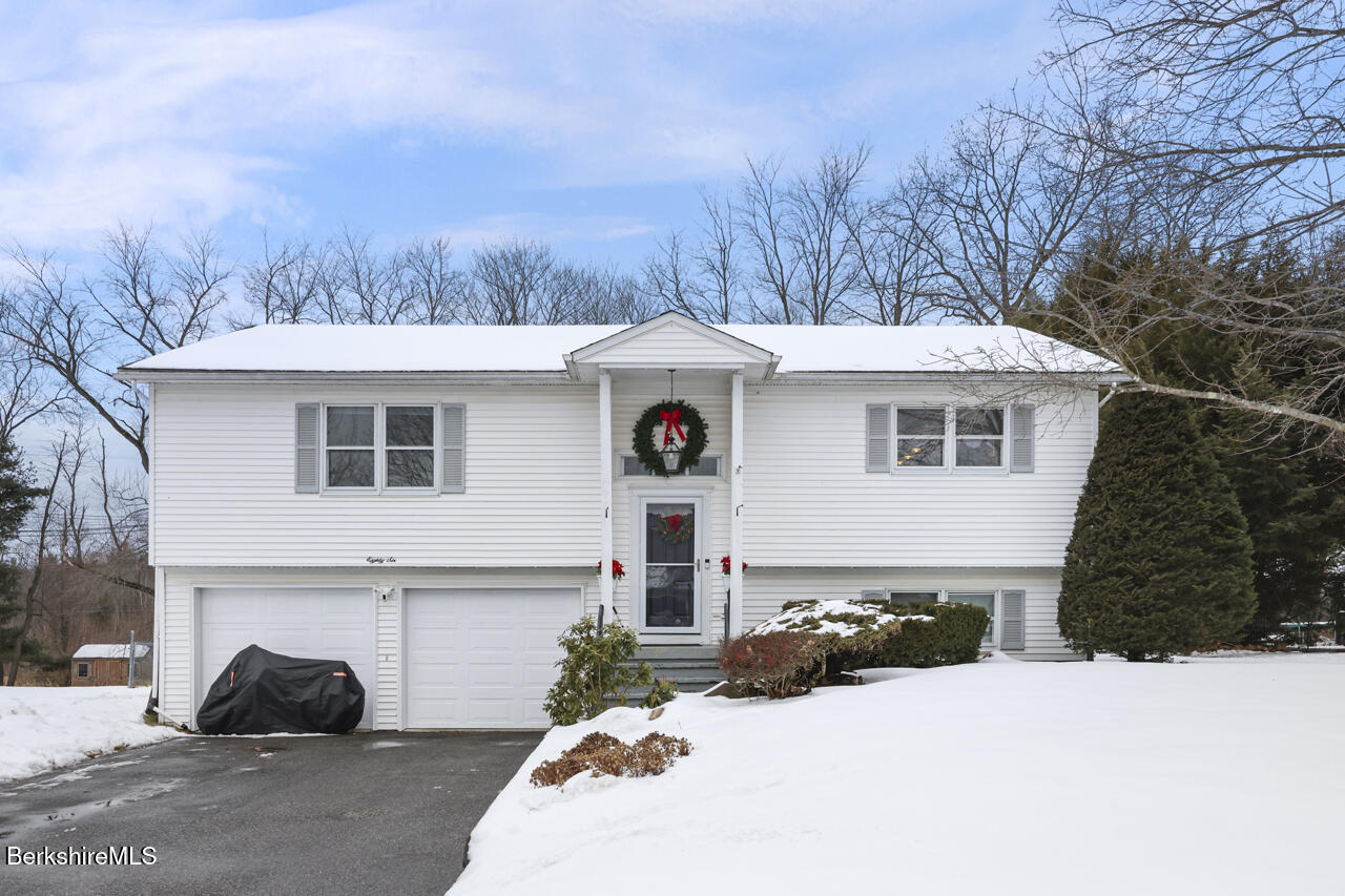 a view of a white house with a yard and large trees