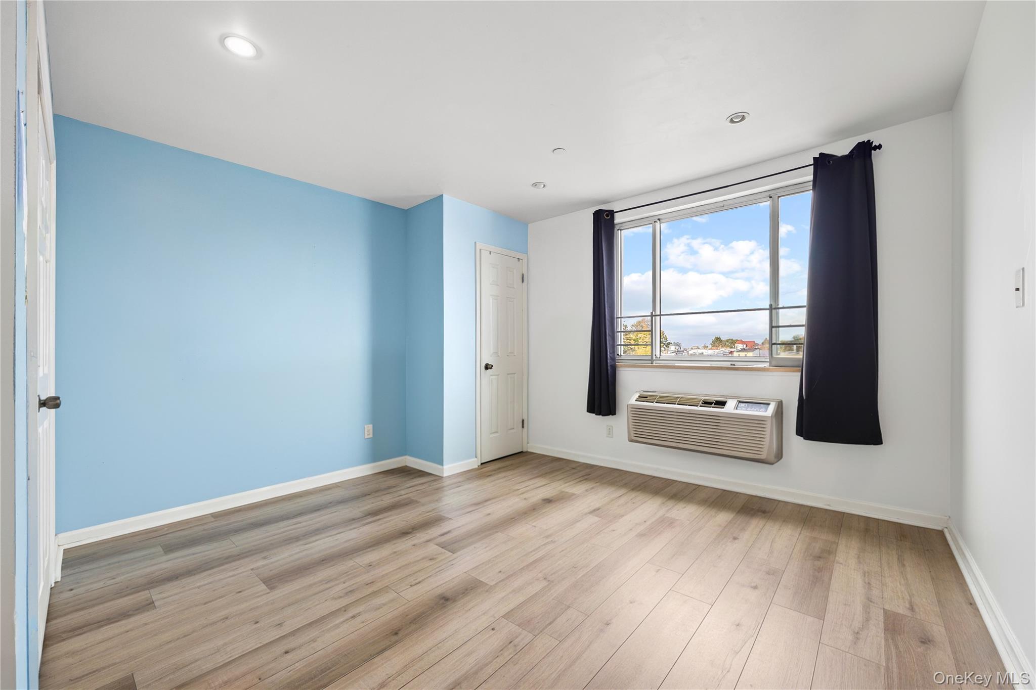 106-07 Northern Boulevard, Unit 5B Queens, NY 11368 - Photo 11 of 18 an empty room with wooden floor and windows