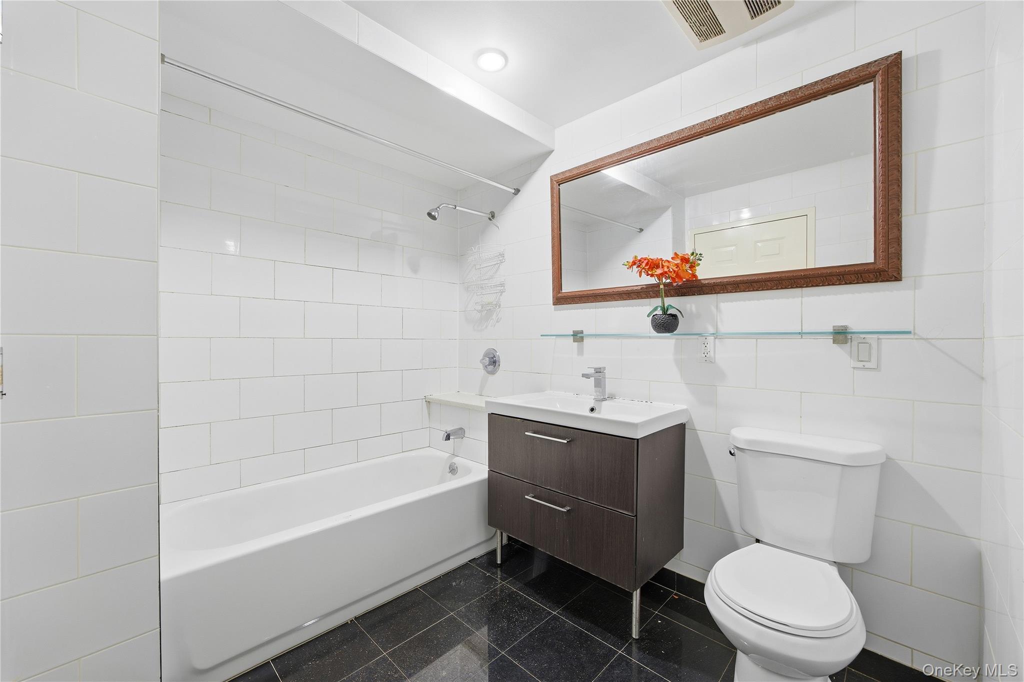 106-07 Northern Boulevard, Unit 5B Queens, NY 11368 - Photo 6 of 19 a bathroom with a toilet a sink and mirror