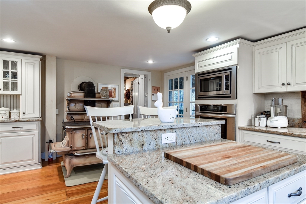 86 Fowler Street Upton, MA 01568 - Photo 9 of 42 a kitchen with stainless steel appliances granite countertop a stove top oven a sink dishwasher and white cabinets with wooden floor