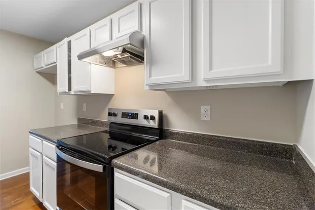 a kitchen with a stove and white cabinets