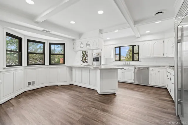 a kitchen with stainless steel appliances kitchen island wooden floors and white cabinets