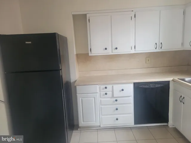 a kitchen with white cabinets and refrigerator