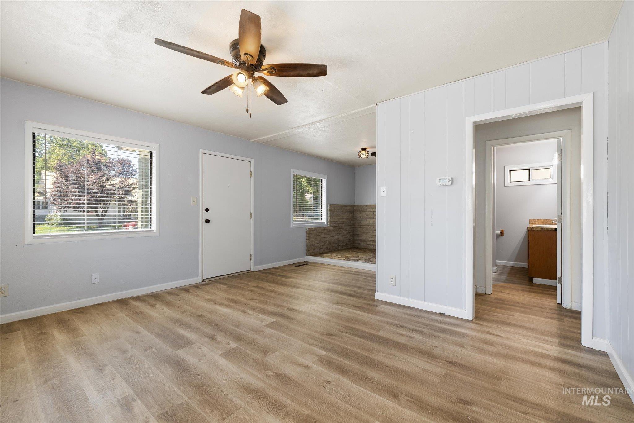 918 West 3rd Street Weiser, ID 83672 - Photo 6 of 36 Bright living area featuring wood-finish flooring, light gray walls, and a ceiling fan with integrated lighting