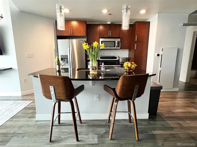 a kitchen with stainless steel appliances a refrigerator a stove a sink cabinets and a dining table