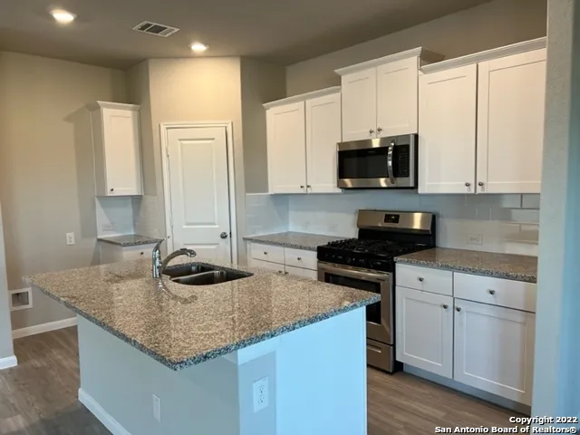 a kitchen with granite countertop a sink a stove and cabinets
