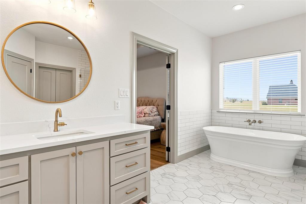 803 Willow Moon Ranch Road Crawford, TX 76638 - Photo 17 of 37 Bathroom with a freestanding soaking tub, white subway tile wainscoting, and large hexagonal floor tiles