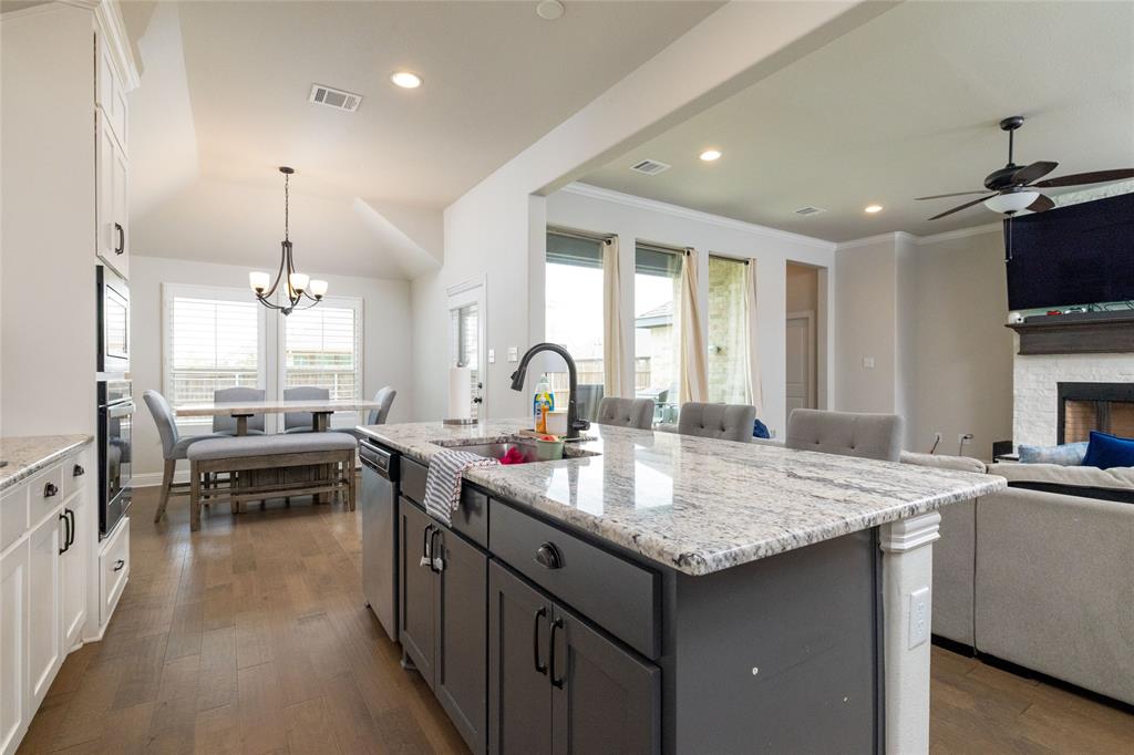 4045 Grove Valley Road Midlothian, TX 76065 - Photo 34 of 34 Dual tone kitchen with open floor plan, light stone countertops, dark wood-style floors, a kitchen island with sink, and suspended lighting