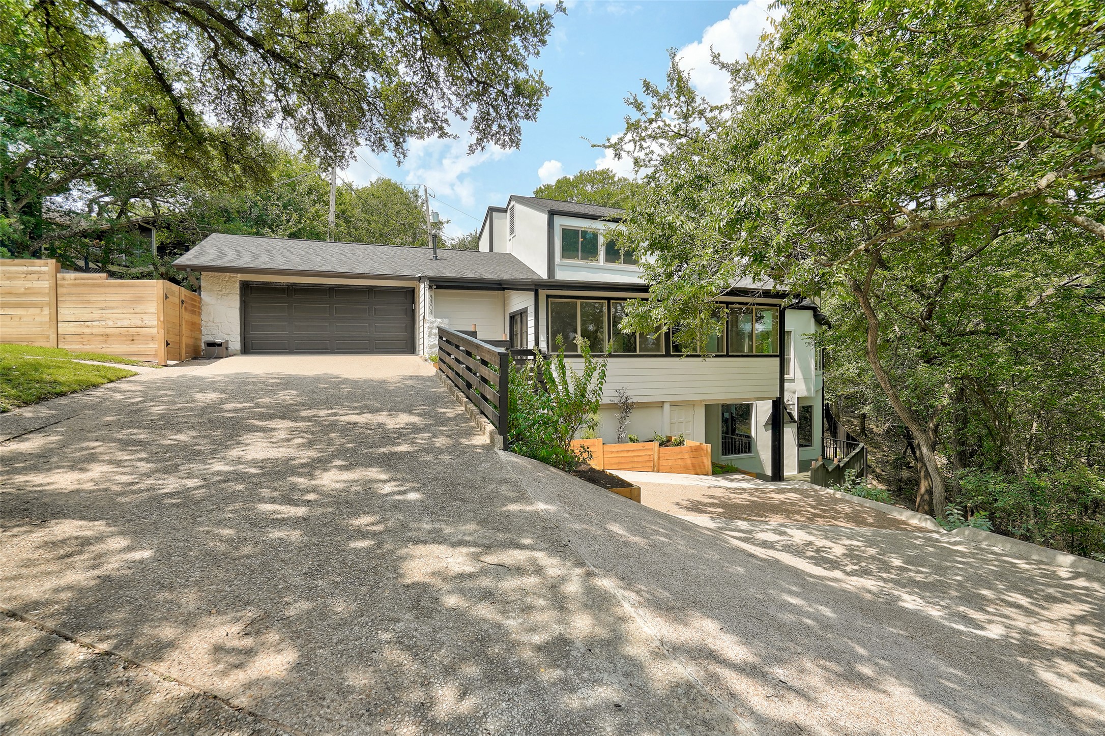 Mid-century modern home featuring driveway, an attached garage, and a shingled roof