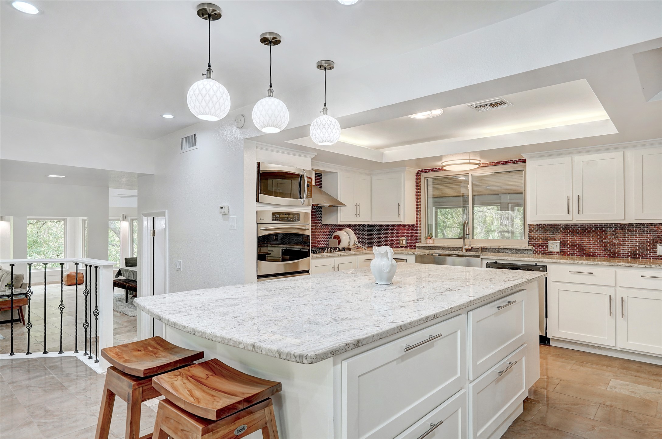 8804 Mountain Ridge Drive, Unit A Austin, TX 78759 - Photo 12 of 37 Kitchen with a kitchen island, stainless steel appliances, light stone counters, a kitchen breakfast bar, and decorative backsplash