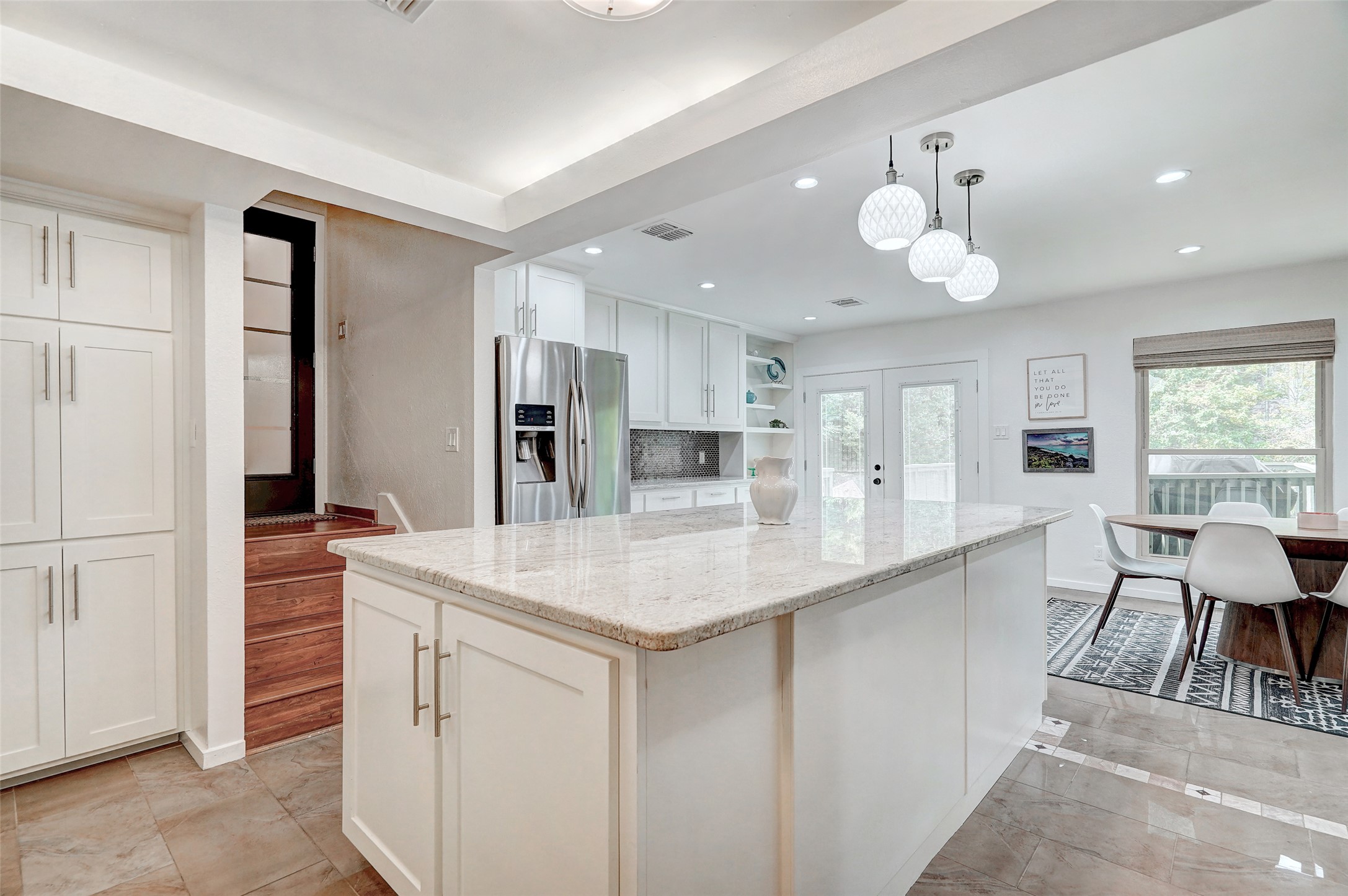 8804 Mountain Ridge Drive, Unit A Austin, TX 78759 - Photo 15 of 37 Kitchen with hanging light fixtures, a kitchen island, stainless steel refrigerator with ice dispenser, white cabinetry, and light stone countertops