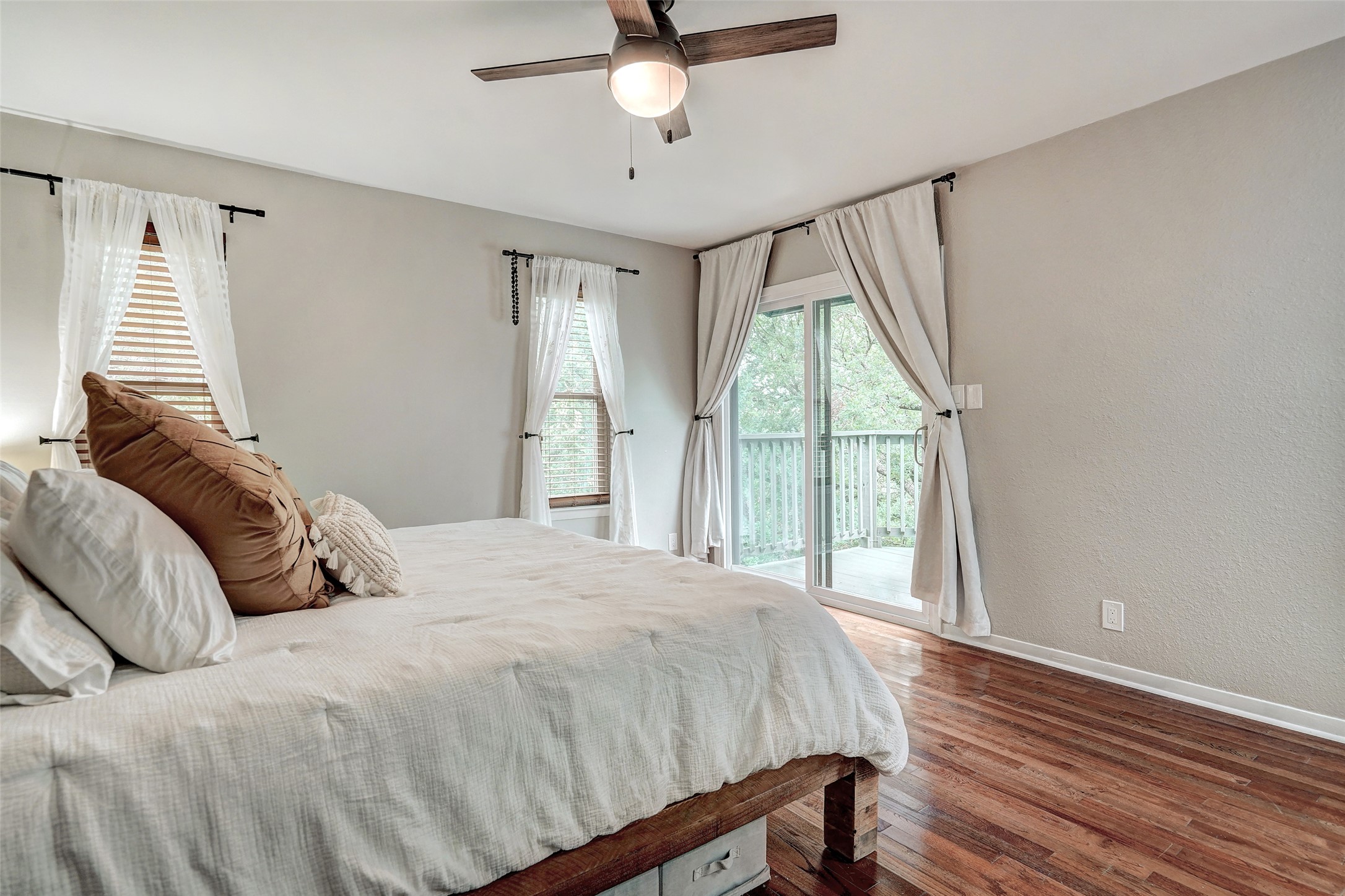 8804 Mountain Ridge Drive, Unit A Austin, TX 78759 - Photo 20 of 37 Bedroom with dark wood finished floors, ceiling fan, access to exterior, and a textured wall