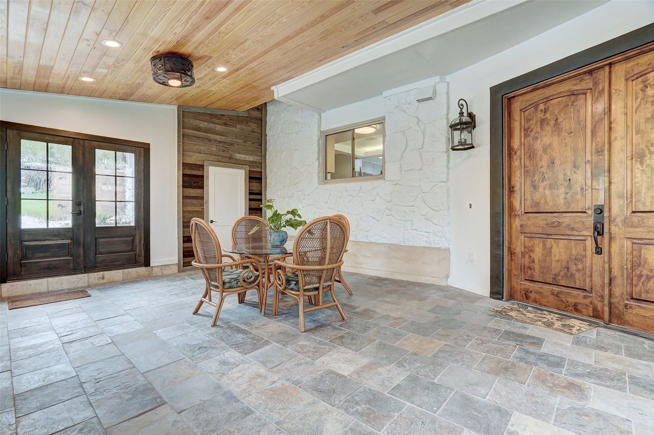 8804 Mountain Ridge Drive, Unit A Austin, TX 78759 - Photo 5 of 37 Dining space with french doors, stone tile floors, recessed lighting, a vaulted wooden ceiling, and an accent wall