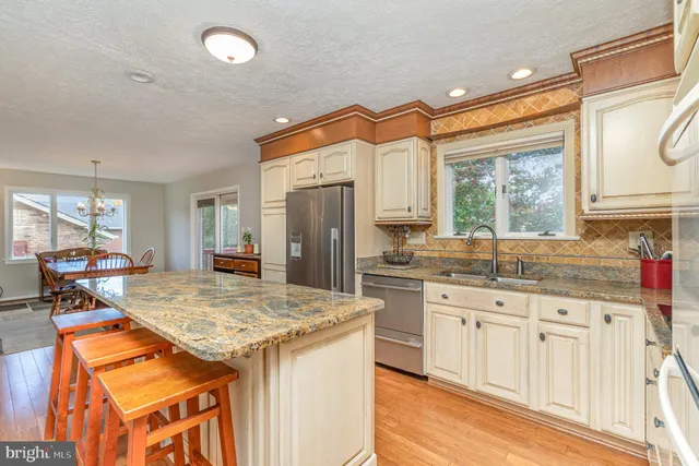 a kitchen with granite countertop kitchen island stainless steel appliances a sink stove and cabinets