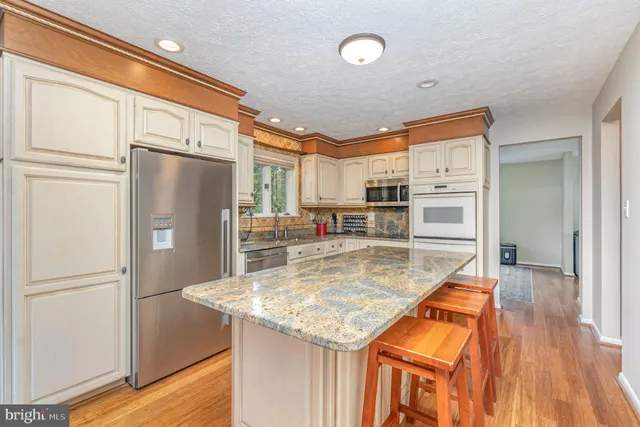 a kitchen with stainless steel appliances granite countertop a refrigerator a stove and a sink