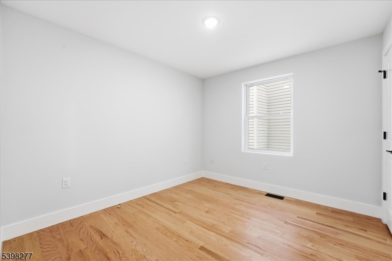 62 Hillside Avenue, Unit 1 Newark, NJ 07108 - Photo 5 of 10 an empty room with wooden floor and windows