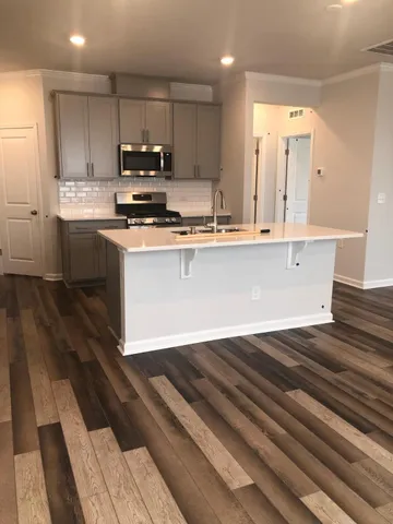 a kitchen with kitchen island granite countertop a sink cabinets and stainless steel appliances