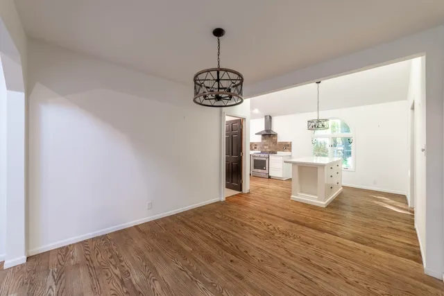 a large kitchen with kitchen island a stove a sink dishwasher a dining table and chairs with wooden floor