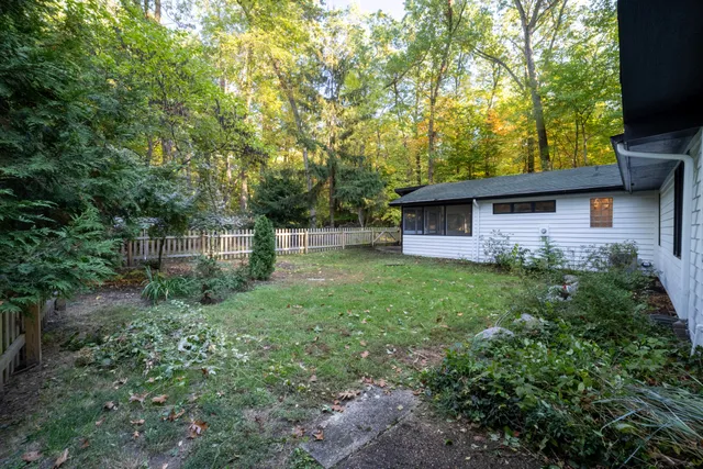 a view of a house with a yard and large trees