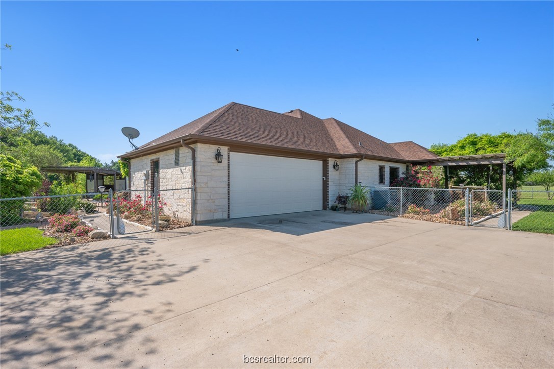7754 Edge Cut Off Road Hearne, TX 77859 - Photo 35 of 49 View of front of home with an attached garage, stone siding, fence, concrete driveway, and a gate
