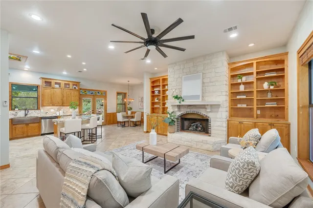 a living room with furniture a fireplace and a dining table with kitchen view
