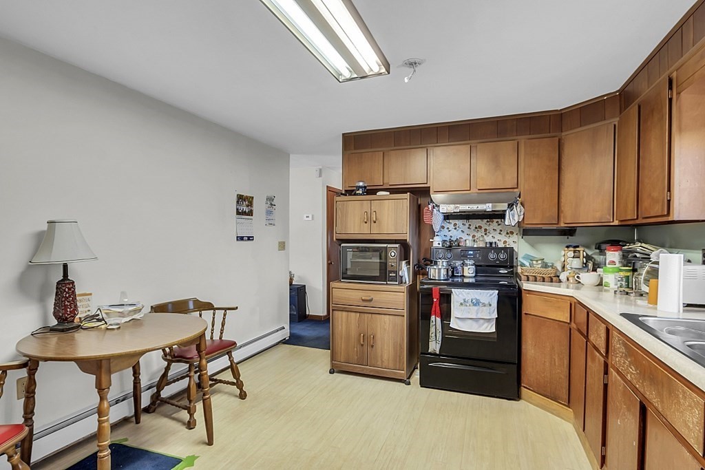 320 Bolton Road Lancaster, MA 01523 - Photo 10 of 28 a kitchen with stainless steel appliances kitchen island a table chairs microwave and sink