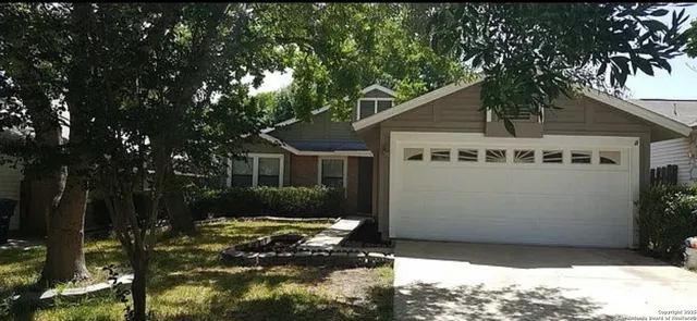 a view of a white house with a large tree