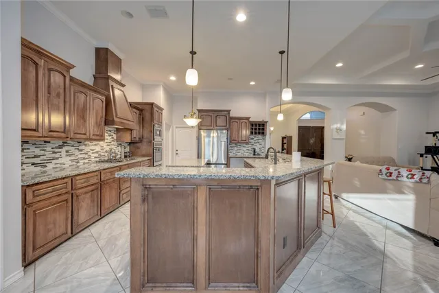 a kitchen with stainless steel appliances granite countertop a sink a stove and a wooden cabinets