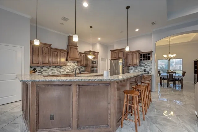 a kitchen with stainless steel appliances kitchen island granite countertop a table chairs and a refrigerator