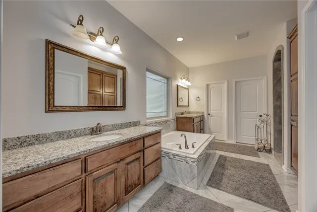 a bathroom with a granite countertop sink mirror and bathtub
