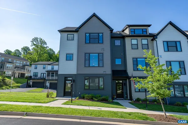 a view of a brick house with a yard and large trees
