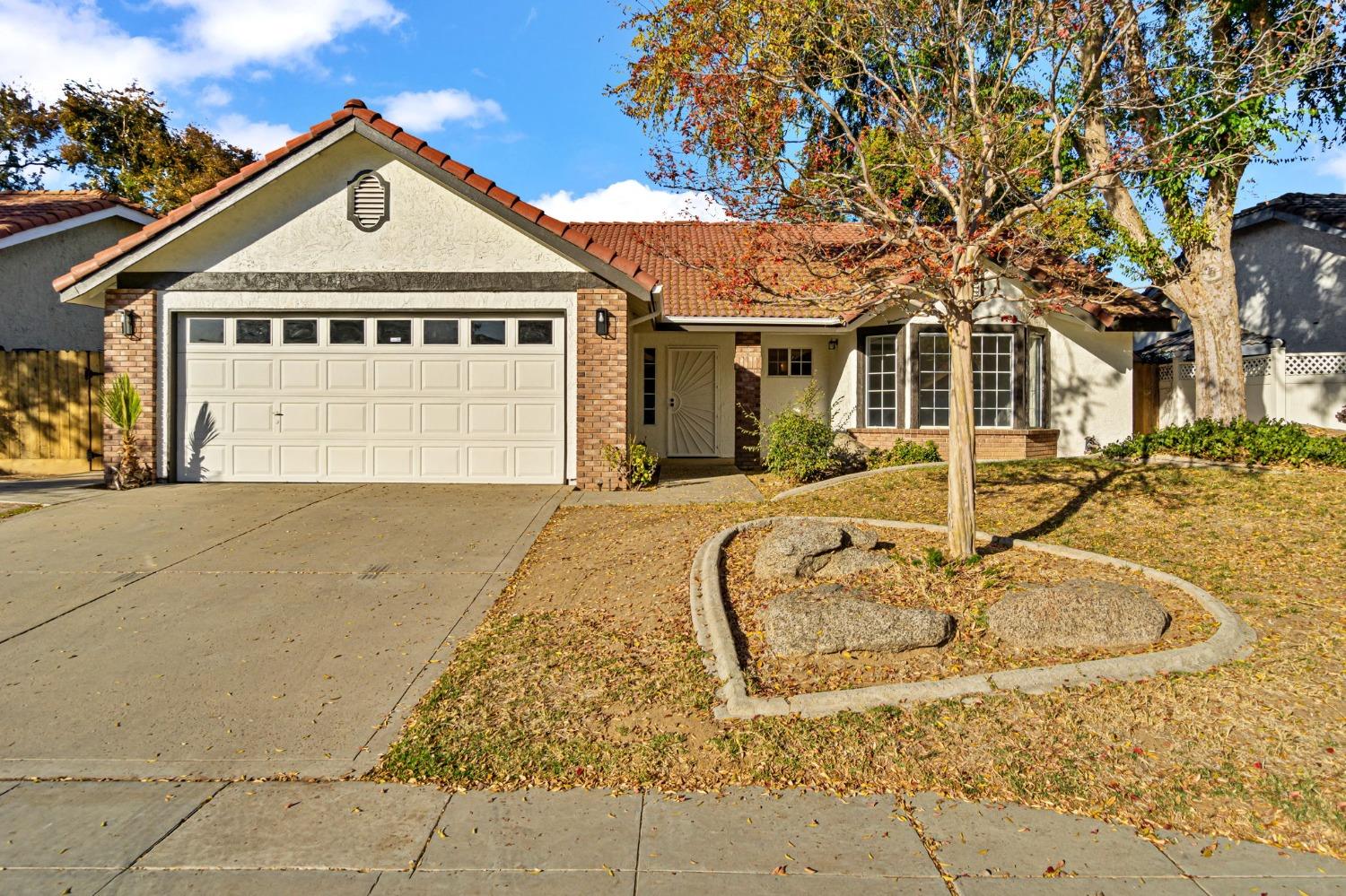 a front view of a house with basket ball court and a tree