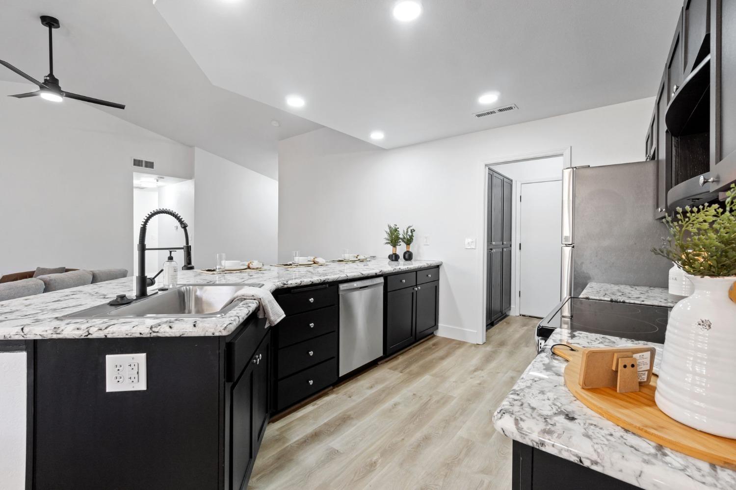 2481 Gibson Avenue Clovis, CA 93611 - Photo 11 of 24 a kitchen with granite countertop a sink stainless steel appliances and white cabinets