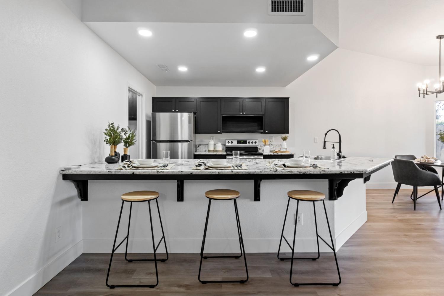 2481 Gibson Avenue Clovis, CA 93611 - Photo 8 of 24 a kitchen with granite countertop a table chairs sink and microwave