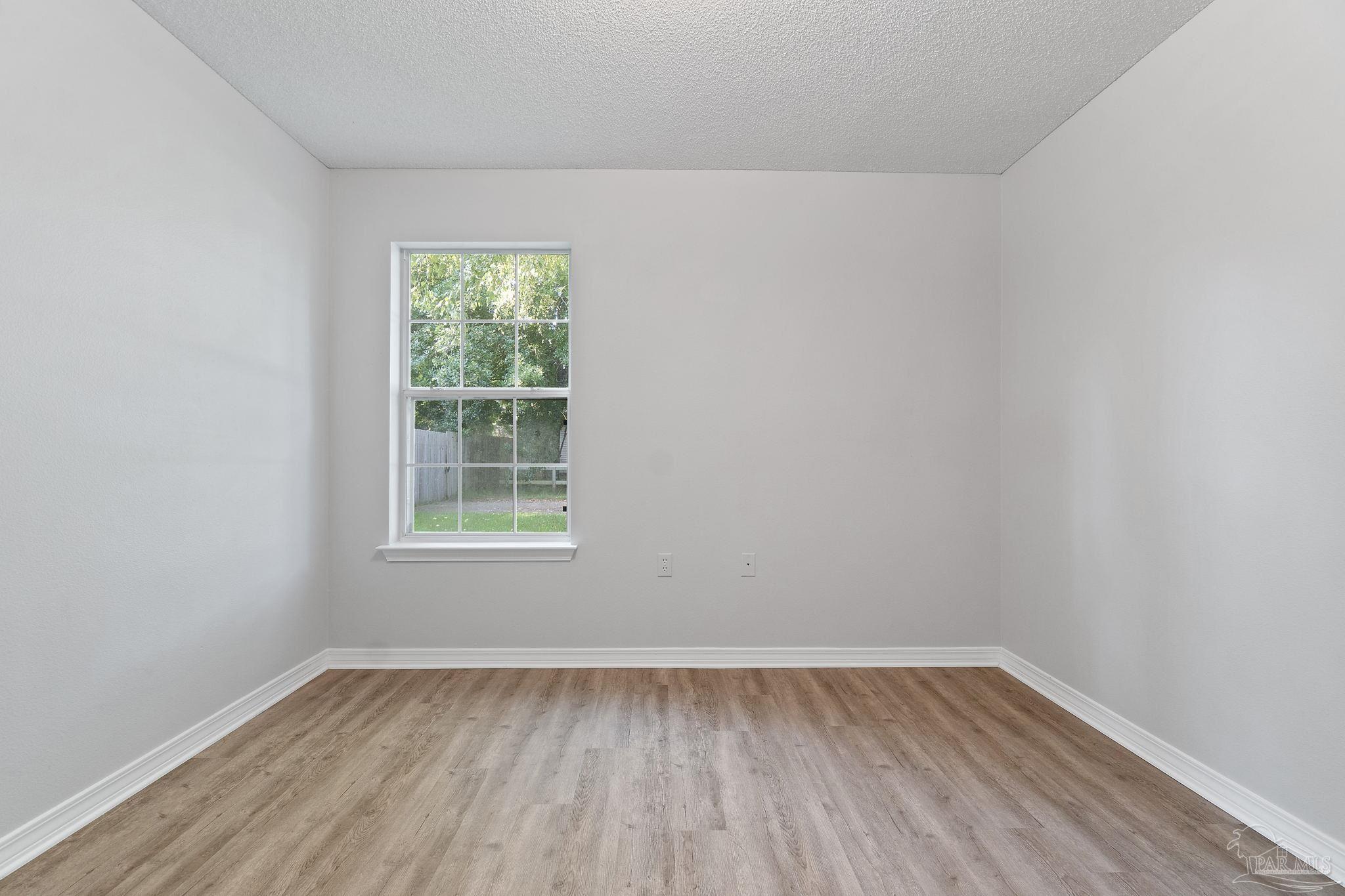 6216 Billoree Road Milton, FL 32571 - Photo 10 of 50 a view of an empty room with wooden floor and a window