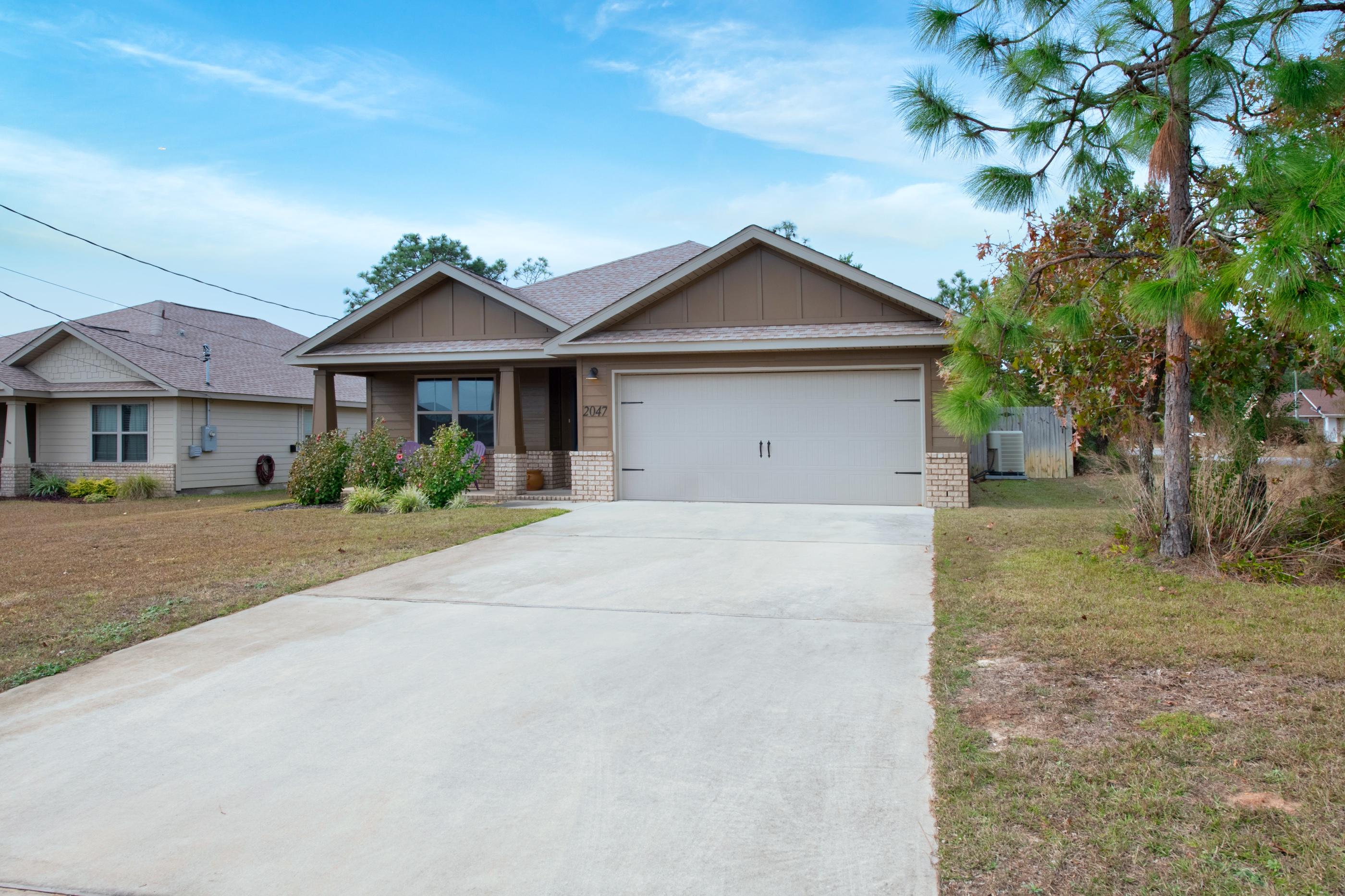 2047 Alhambra Street Navarre, FL 32566 - Photo 3 of 24 a front view of a house with a yard and garage