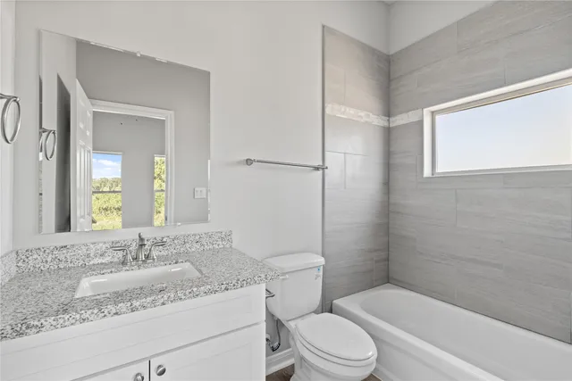 a bathroom with a granite countertop sink toilet mirror and bathtub