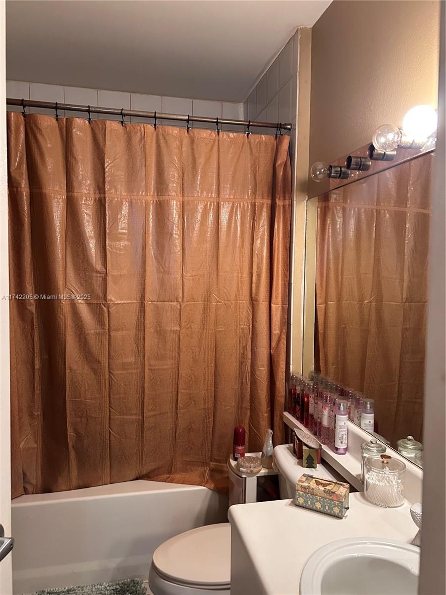 7940 North Nob Hill Road, Unit 201 Tamarac, FL 33321 - Photo 8 of 10 a bathroom with a bathtub and a shower curtain