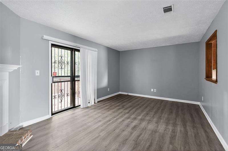 5957 Friar Court, Unit A Atlanta, GA 30349 - Photo 7 of 16 wooden floor in an empty room with a window