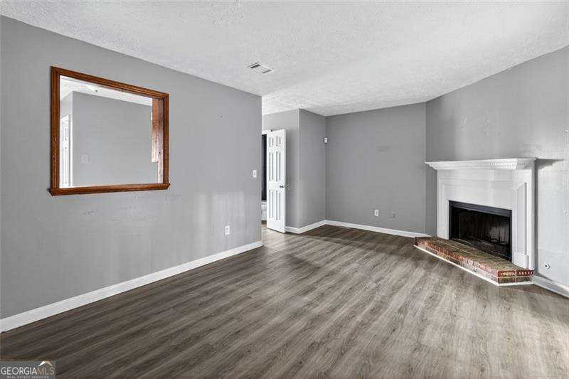 5957 Friar Court, Unit A Atlanta, GA 30349 - Photo 8 of 16 a view of an empty room with wooden floor fireplace and a window