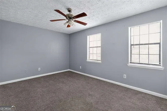 an empty room with windows and fan