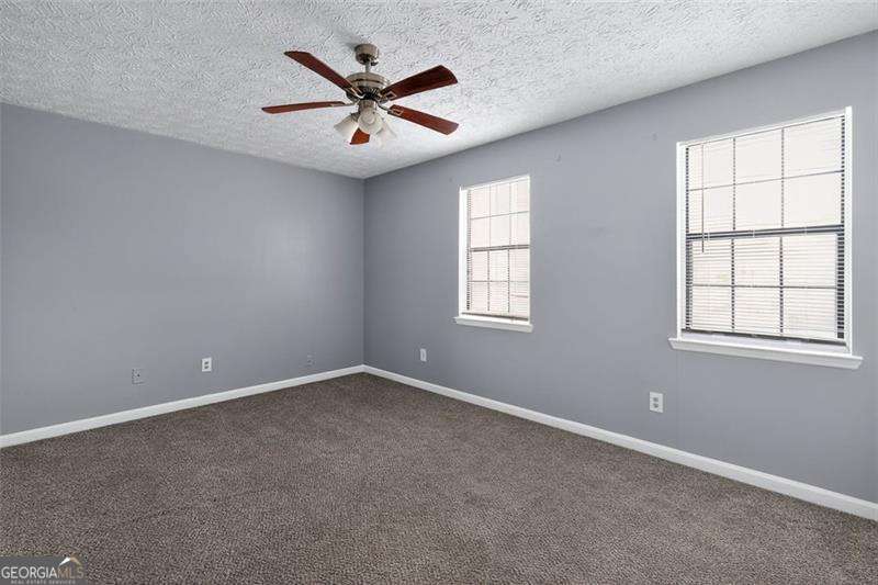 5957 Friar Court, Unit A Atlanta, GA 30349 - Photo 10 of 16 an empty room with windows and fan