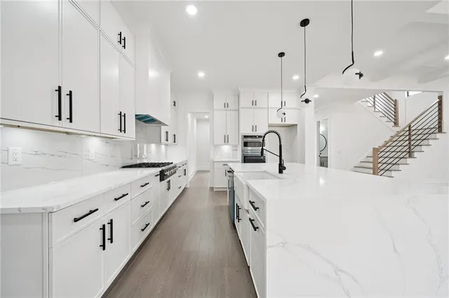 a large kitchen with stainless steel appliances kitchen island a large counter top a stove a sink and a refrigerator