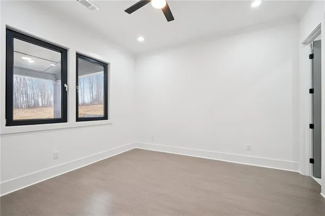 an empty room with chandelier fan and windows