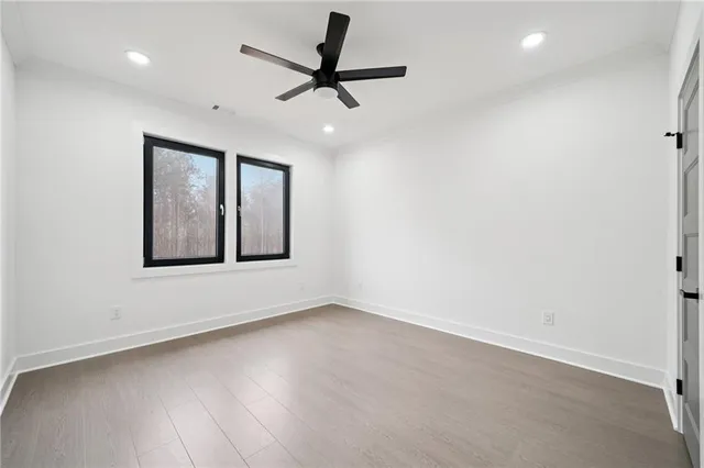 an empty room with wooden floor ceiling fan and windows