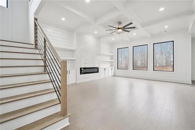 a view of an empty room with wooden floor and ceiling fan