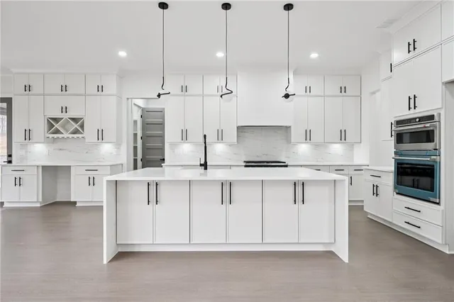 a kitchen with stainless steel appliances kitchen island granite countertop a stove a sink and white cabinets
