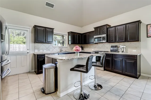 a kitchen with kitchen island granite countertop a stove top oven a sink a counter space and cabinets