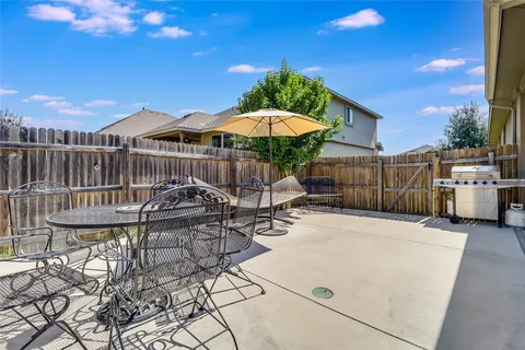 a view of a patio with a table and chairs under an umbrella with wooden fence