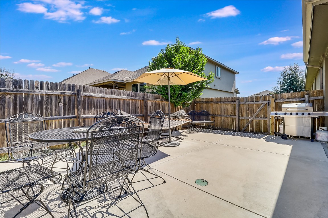 1425 Hamiltons Way Leander, TX 78641 - Photo 38 of 38 a view of a patio with a table and chairs under an umbrella with wooden fence